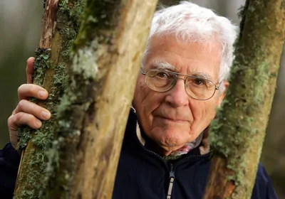 A headshot of James Lovelock standing between tree trunks A headshot of James Lovelock standing between tree trunks